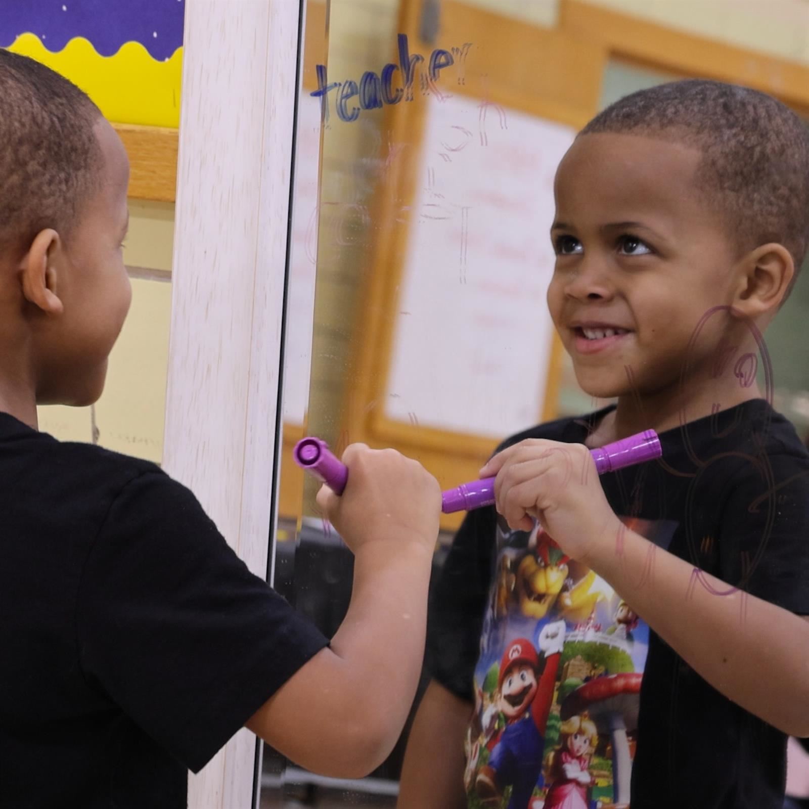  A student writes on a mirror with a dry erase pen